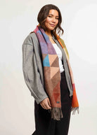 Woman wearing a colorful geometric patterned scarf on a plain background