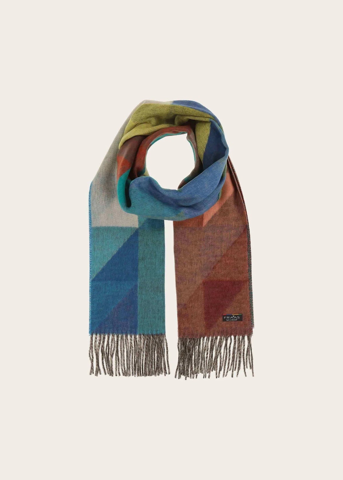 A multicolor geometric patterned scarf with fringed ends, displayed on a neutral cream background. The scarf features blocks of blue, teal, rust orange, olive green, and light gray.