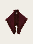 A deep burgundy shawl with plush, fluffy trim along the edges, displayed flat against a light off-white background.