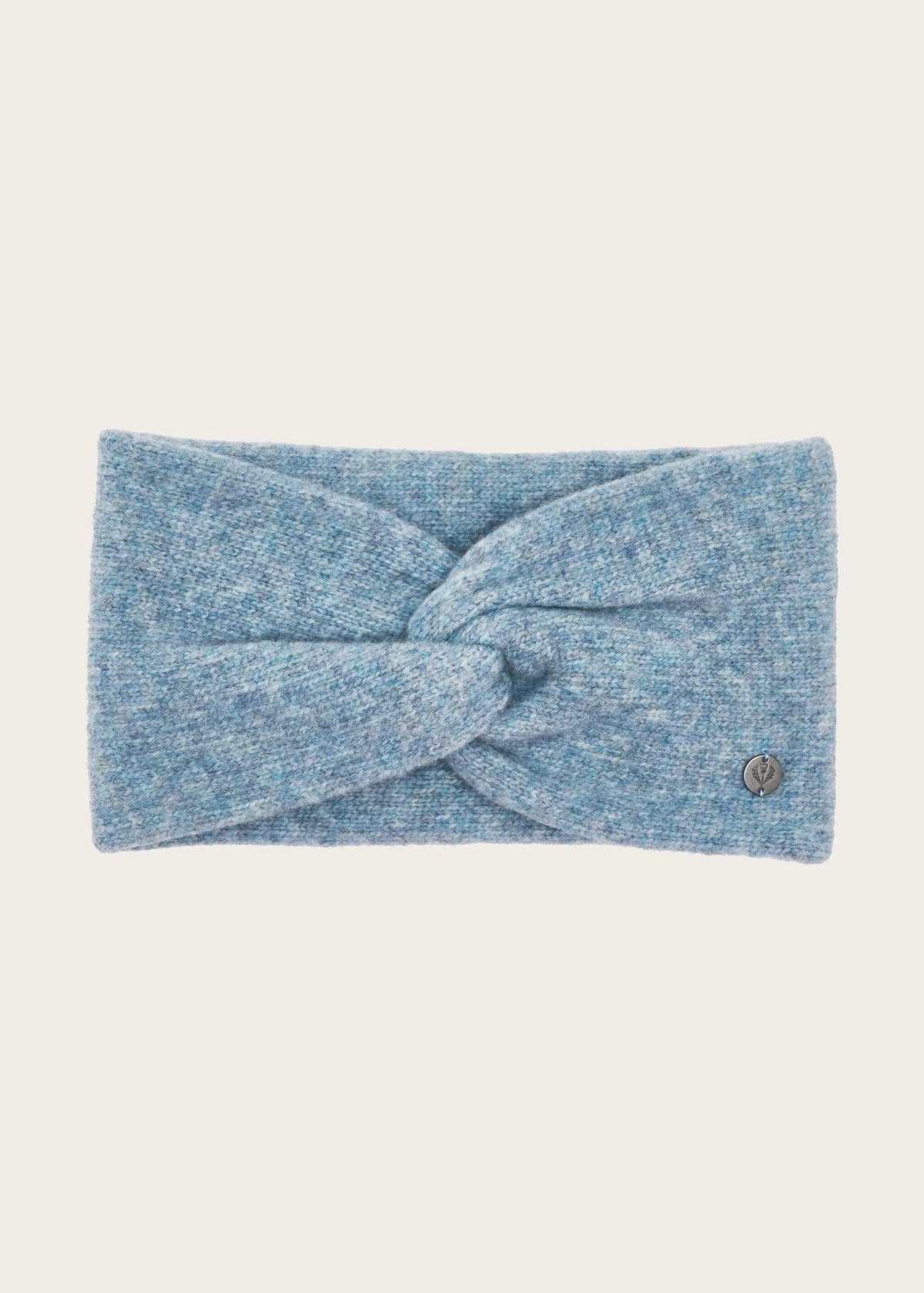 A light blue heathered knit headband with a central twisted knot and a small metallic logo emblem on the right side, shown against a solid off-white background.