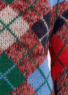 Close-up of a textured knit sweater featuring a multicolor argyle pattern with red, green, light blue, cream, and dark navy diamonds.